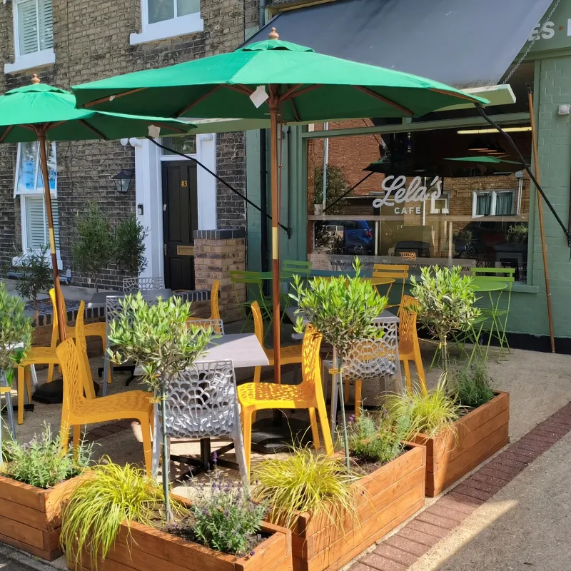 Lela's Cafe storefront with green parasols and yellow chairs